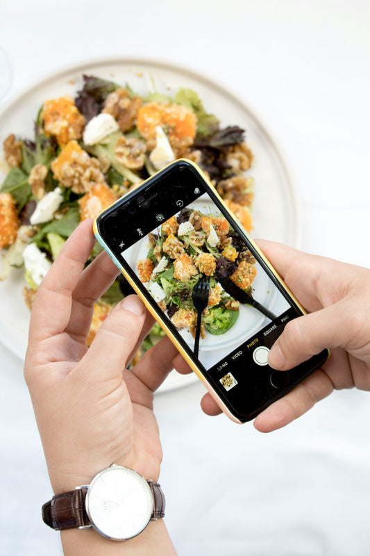 Photo of person taking a photo of a plate of food with their cell phone